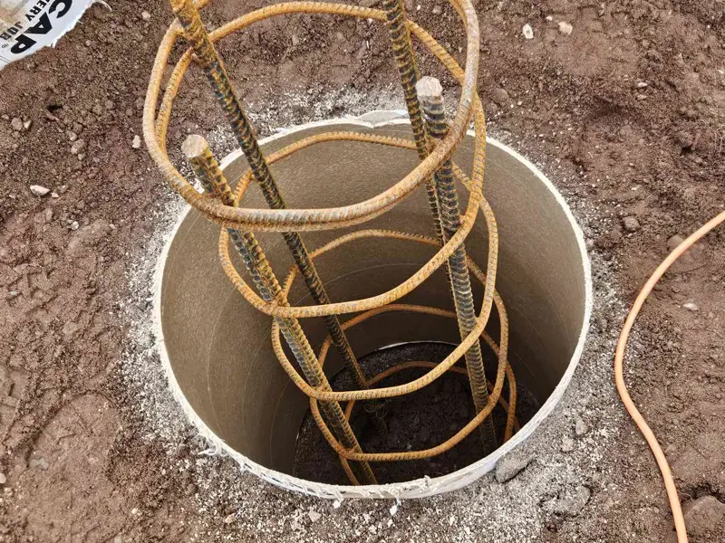 Rebar cage standing in a tube form inside an excavated footing